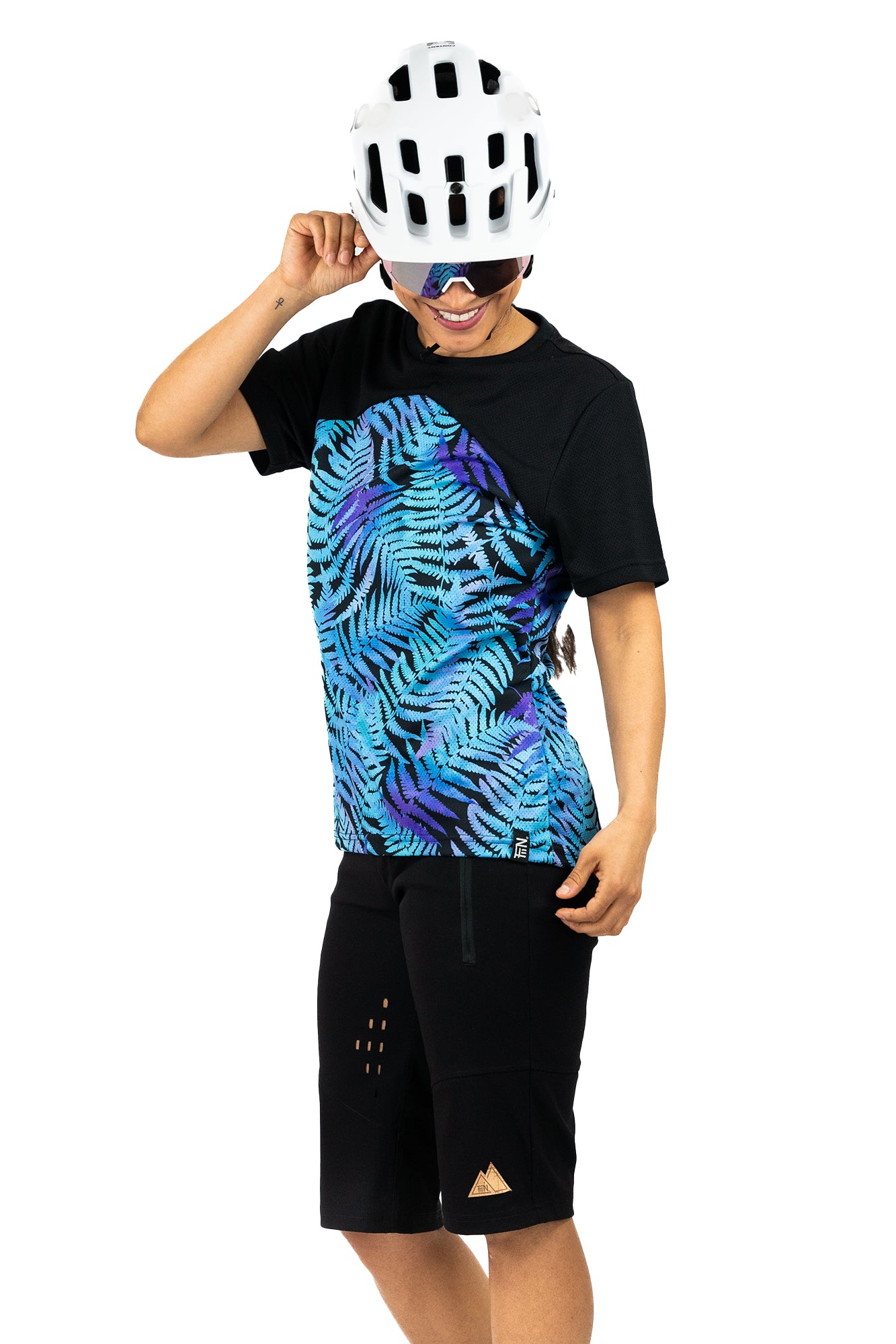 Mountainbike Short für Frauen in schwarz mit tiefem Hosenbund und atmungsaktiven Lüftungsschlitzen in Kombination mit Kurzarm Mountainbikejersey für Frauen in der Farbe schwarz und blau-lila mit floralem Farn Print