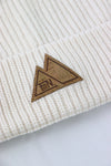 Detail FiiN Label aus Kork auf dem cremefarbenen Beanie. Vorne, mittig aufgenäht an der breiten Krempe der grob gestickten Mütze.